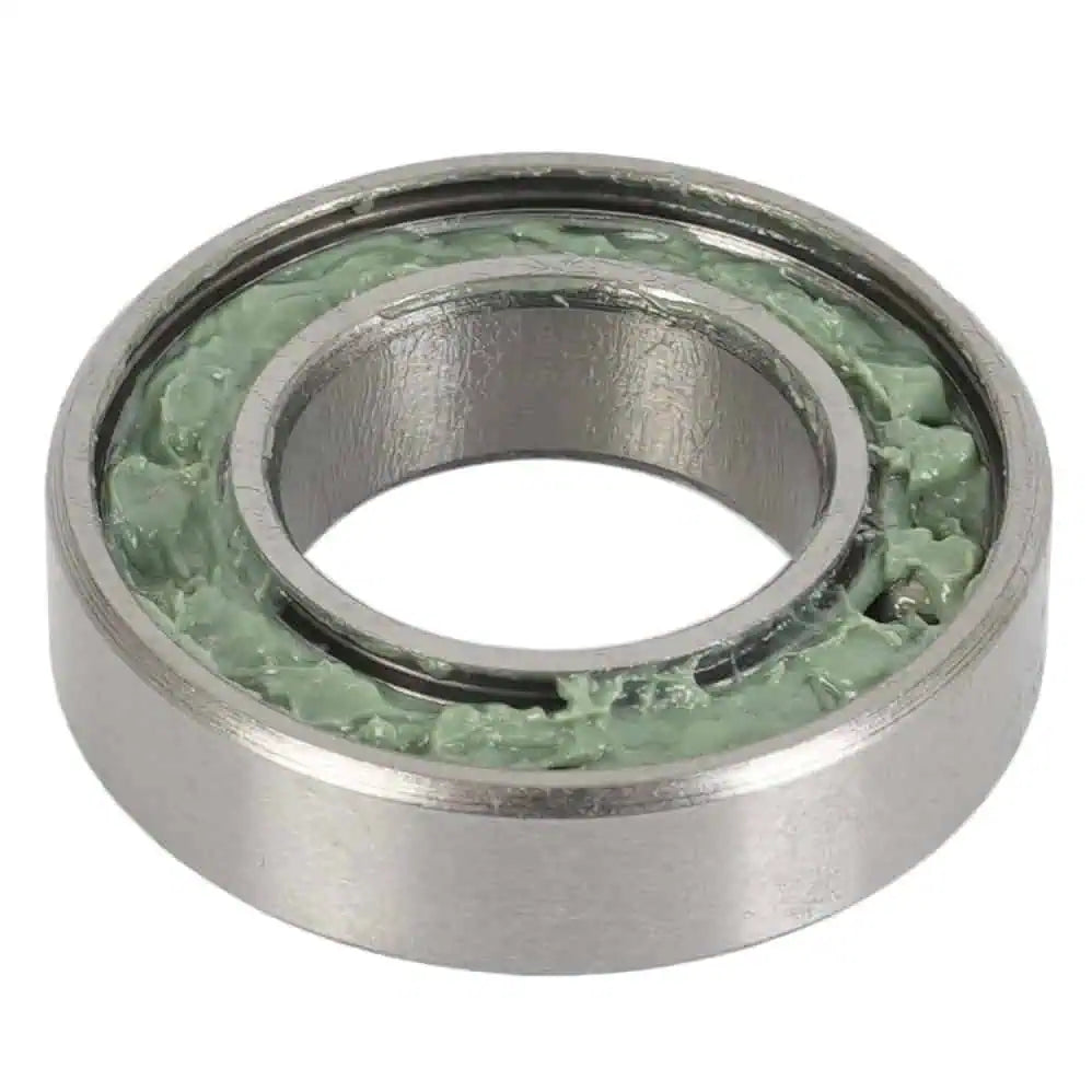 Metal bearing filled with green grease and has a single metal dust shield on a white background