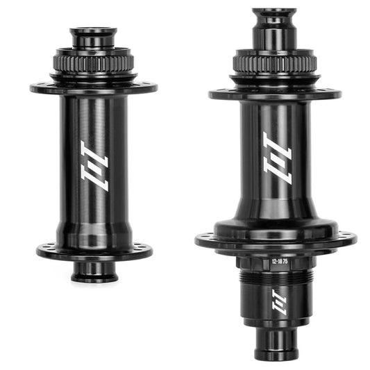 Two black Industry Nine bicycle hubs shown side by side on a plain white background, each with a white stylized 1/1 logo printed on the center body.